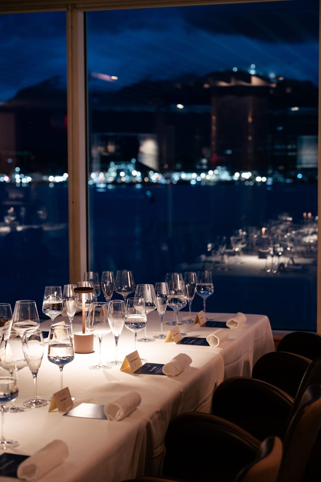 A table set at night at Five Sails, with the harbour and the city behind